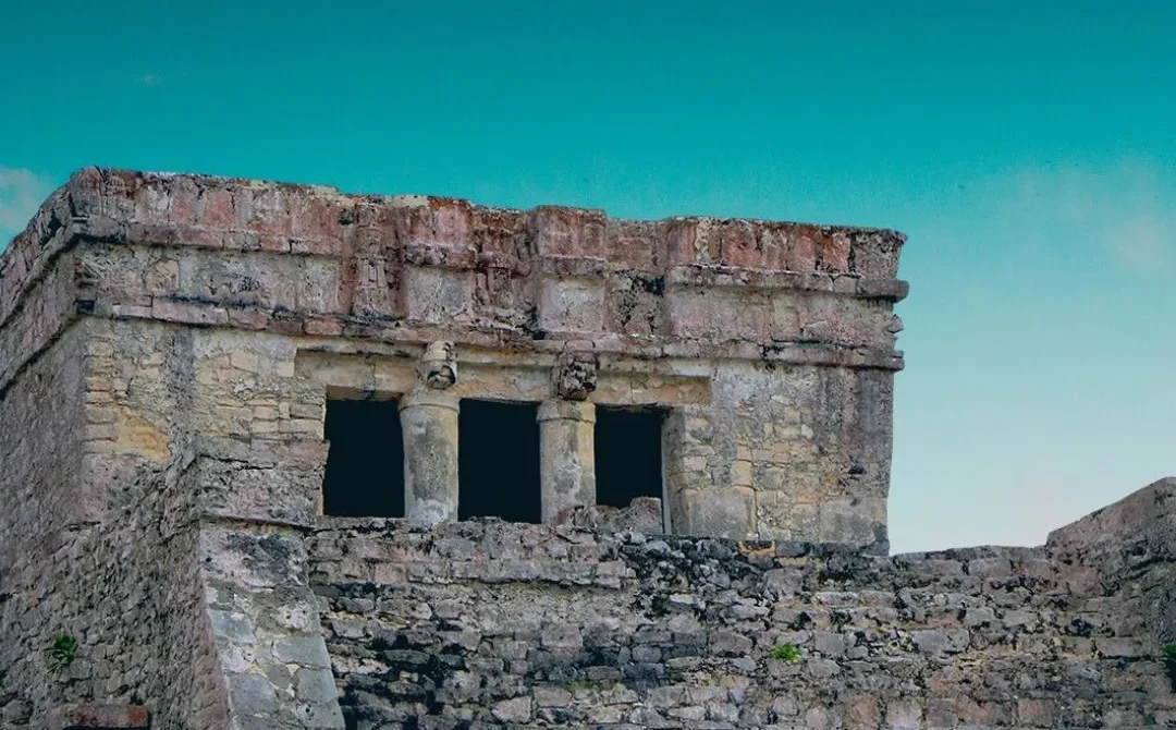Ruinas arqueológicas de un edificio maya rodeado de un cielo azul claro