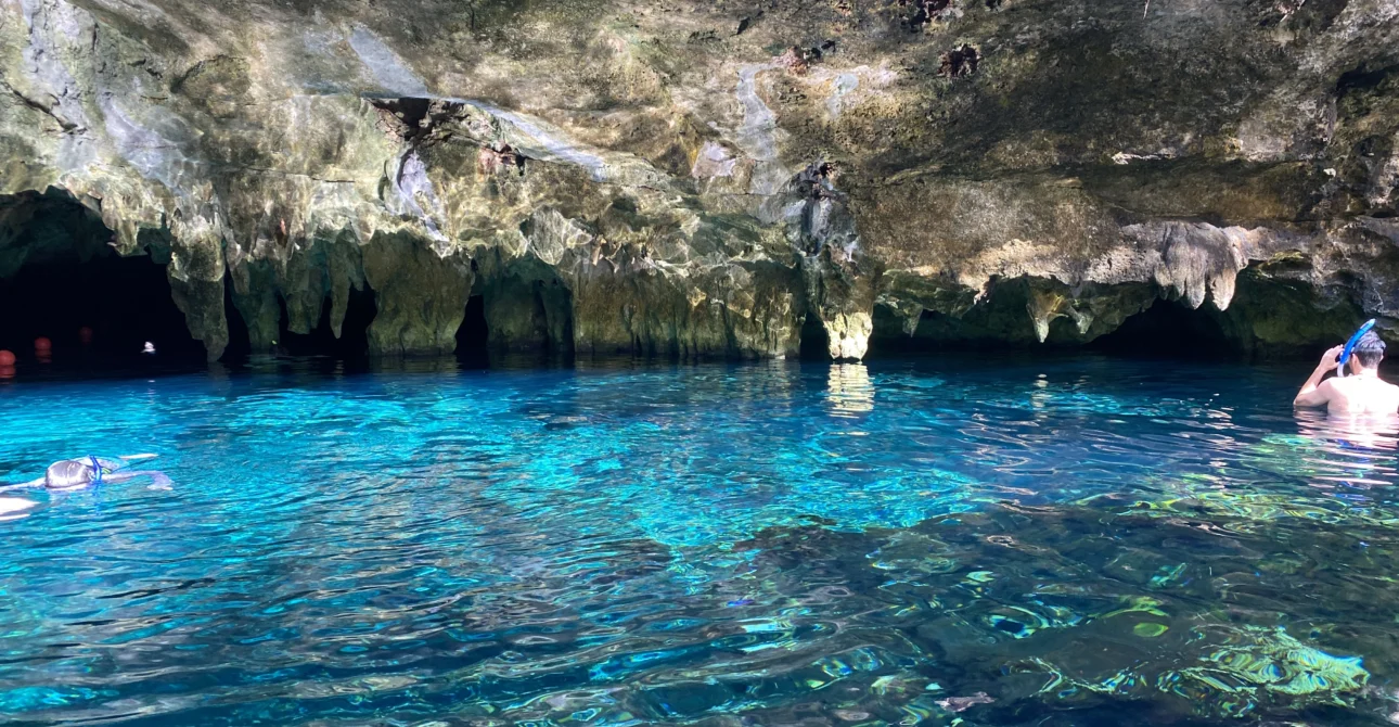 Vista de un cenote cristalino con formaciones rocosas naturales y aguas turquesas.